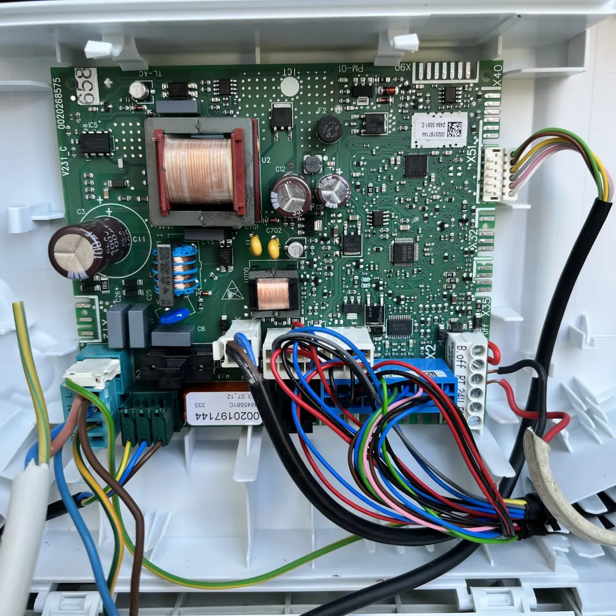 An appliance control board with its wiring harness, opened up inside its housing