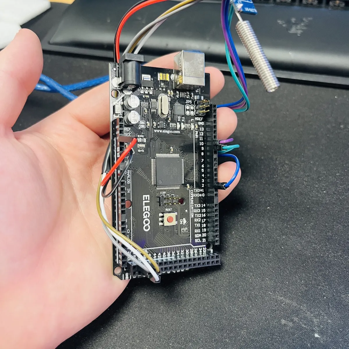 A Mega-format microcontroller board held in hand, wired to a radio module with a coil antenna